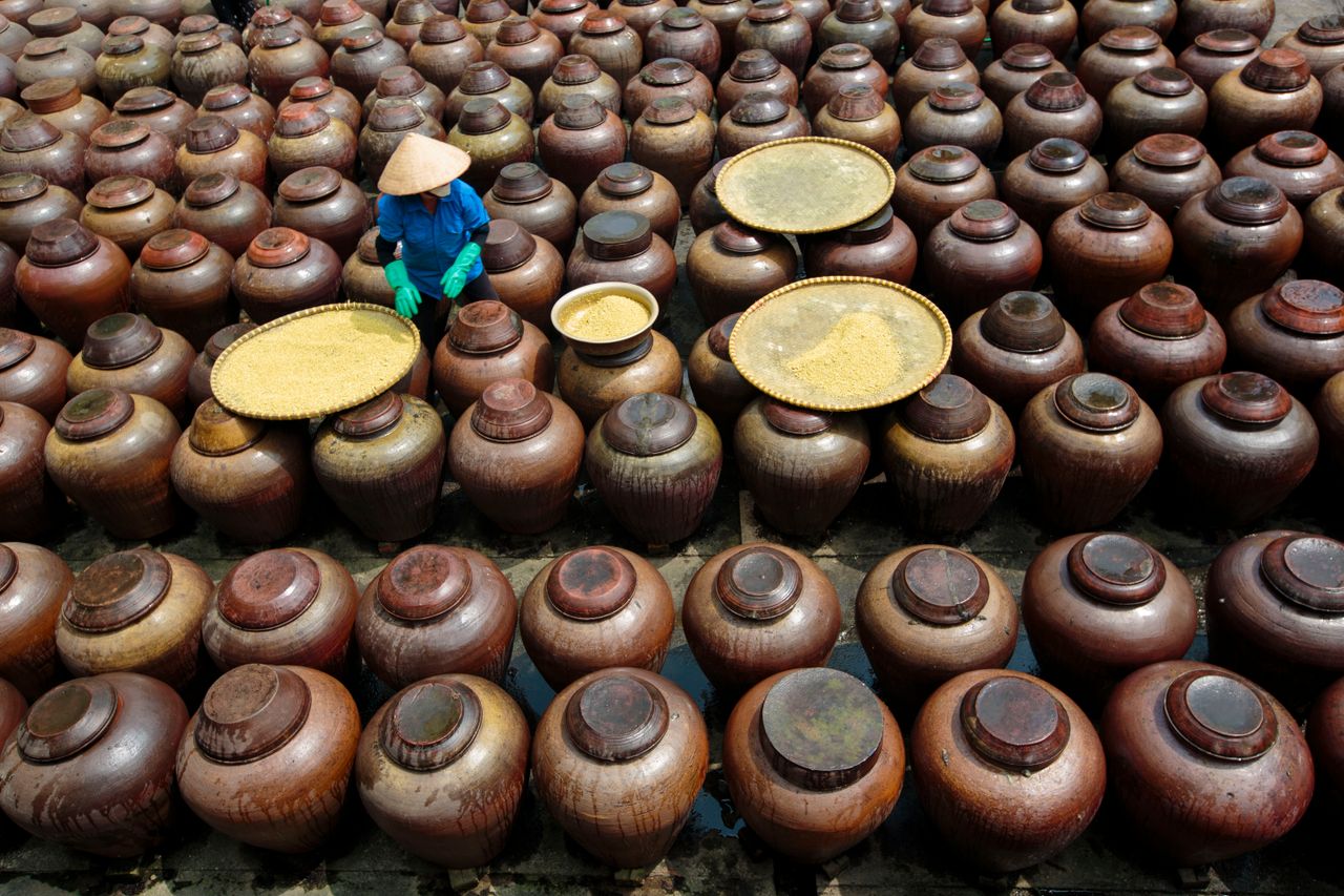 ours-journey Aerial view of a worker arranging fermentation jars in Hưng Yên, Vietnam, highlighting traditional craftsmanship.